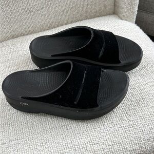 Black OOFOS velvet platform slides.
